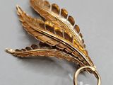 an image of a gold leaf brooch with a ring on it
