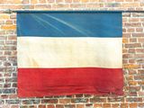 a red, white, and blue flag hanging on a brick wall