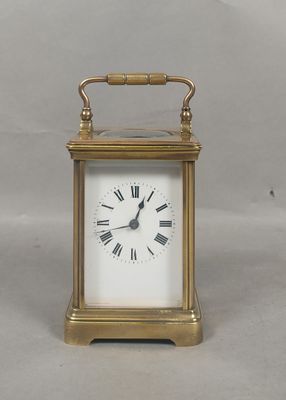 une petite horloge en laiton avec des chiffres romains sur le cadran
