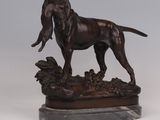 bronze statue of a dog standing on a rock on a marble base