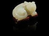 une sculpture en jade blanc représentant un chat, posée sur une surface noire