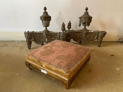 a small ottoman sitting on the floor in front of a bed