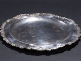 an antique silver plate on a black table with a black background