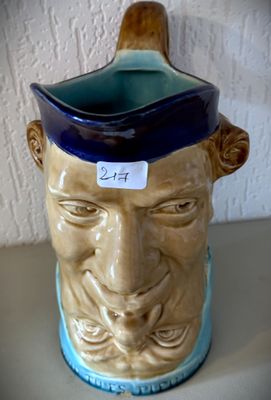 un vase bleu et marron sur lequel est représenté le visage d'un homme