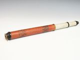 an old cigarette with a red and white tube sitting on top of a white surface