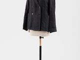une veste noire posée sur un mannequin, avec une chemise rose