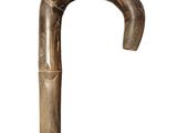 une vieille canne en bois avec un pommeau en métal, sur fond blanc