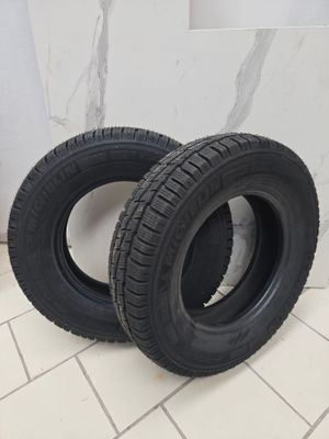 two black tires on a white tiled floor next to a wall