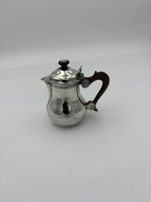 a small silver tea pot with a wooden handle on a white surface