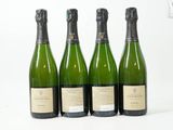quatre bouteilles de champagne sont alignées sur une surface blanche