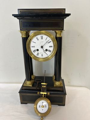 une horloge noire et dorée avec des chiffres romains