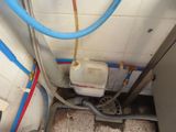 a toilet in a bathroom with pipes and a water tank