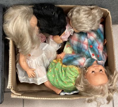 trois poupées dans une boîte en carton posée par terre