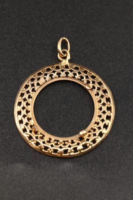 un pendentif plaqué or présentant un motif circulaire sur fond noir