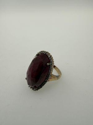 a close up of a ring with a red stone in it