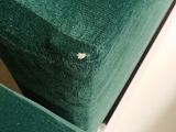 a close up of a green chair with a hole in it