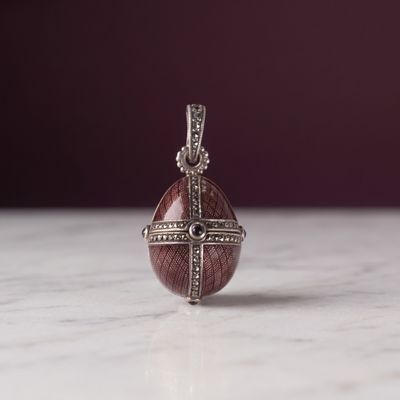 pendentif en argent massif orné d'une pierre rouge et de diamants, sur un fond en marbre