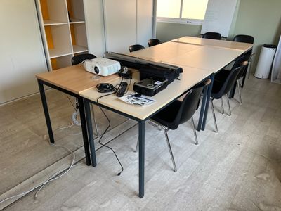 une longue table sur laquelle est posé un projecteur, dans une pièce