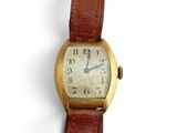 une petite montre-bracelet en or avec un bracelet en cuir marron