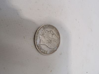 une pièce d'argent posée sur une surface blanche, avec une ombre