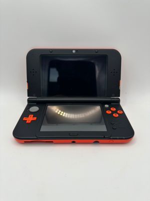 une Nintendo 3DS orange et noire posée sur une table blanche