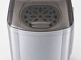 une image représentant une petite machine à laver posée sur une surface blanche
