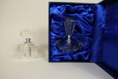 a small glass bottle in a blue box next to a small glass bottle