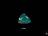 a close up of a green and white diamond on a black surface