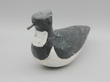 un petit canard noir et blanc posé sur une surface blanche