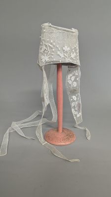 a white hat on a pink stand with a white ribbon