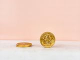 a gold coin next to a gold coin on a pink background