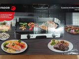 emballage représentant une boîte noire et blanche avec l'image d'un barbecue et d'assiettes de plats posées sur une table