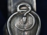 a close up of a silver spoon with a snake on it