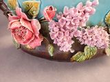a blue vase with pink flowers on it on a table