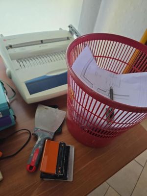 un panier rouge posé sur une table, à côté d'une machine à écrire et d'autres fournitures de bureau