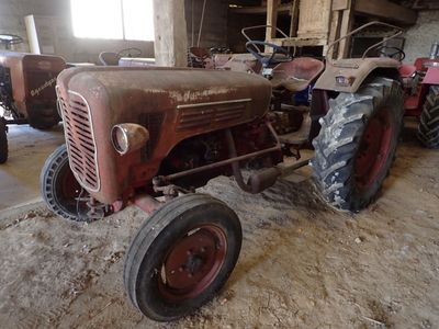 deux vieux tracteurs qui traînent dans une grange, sans roues