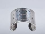 a close up of a silver cuff with holes on it