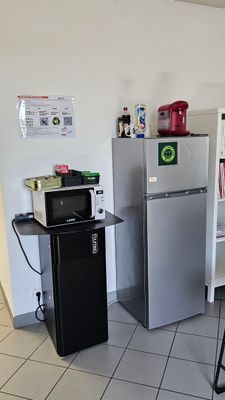 une cuisine équipée d'un réfrigérateur, d'un micro-ondes et d'une étagère