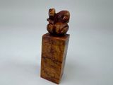 sculpture en bois représentant un ours posé sur un bloc, sur une surface blanche