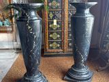 two black vases sitting next to each other on the floor