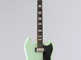 un gros plan d'une guitare électrique verte sur fond blanc