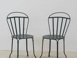une paire de chaises en métal noir avec des assises vertes, posées devant un mur blanc