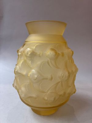 un vase jaune posé sur une surface blanche