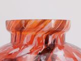 a close up of a vase with a red and white swirl design