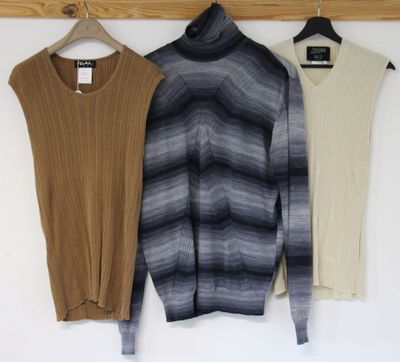 three sweaters hanging on a wooden hanger in front of a white wall