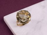 an image of a ring with a yellow topazt stone on a marble surface