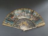 un éventail avec un tableau posé sur une table