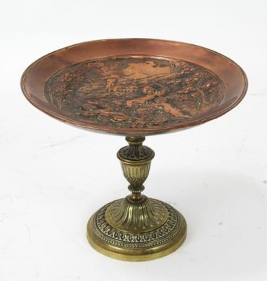 une plaque en laiton ancien posée sur un socle, sur fond blanc