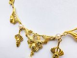 gold plated necklace with pearls and charms on a mannequin