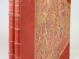 an old red book with gold trim and a decorative cover